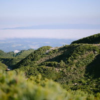 緑の山々に囲まれた山中の十勝岳温泉遠景と登山風景の写真