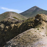 登山道から見上げる日本百名山・十勝岳の山頂の写真