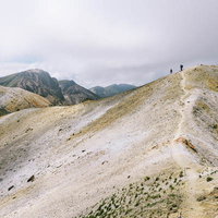 日本百名山・十勝岳の雲が広がる稜線を歩く登山者の写真