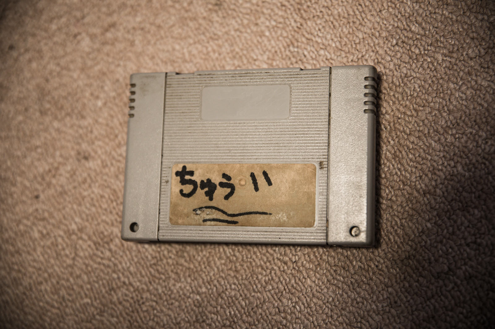 手書きラベルが貼られたスーファミのゲームカセット、グレーケースに茶色いラベル