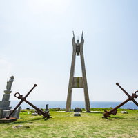 青空の下に立つ戦艦大和慰霊塔の正面、徳之島の海を背景にした慰霊塔の写真