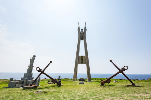 青空の下に立つ戦艦大和慰霊塔の正面、徳之島の海を背景にした慰霊塔