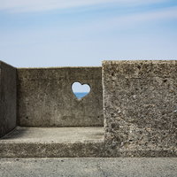 ハート型に穴があいた堤防と海の写真