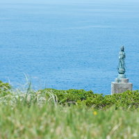 徳之島の犬の門蓋に立つ観音菩薩像と青い海の風景の写真