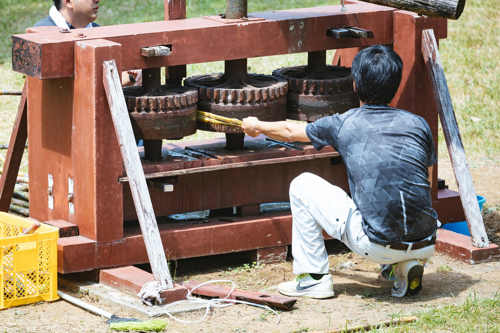 木製のサトウキビ圧搾機サタグンマで作業をする男性