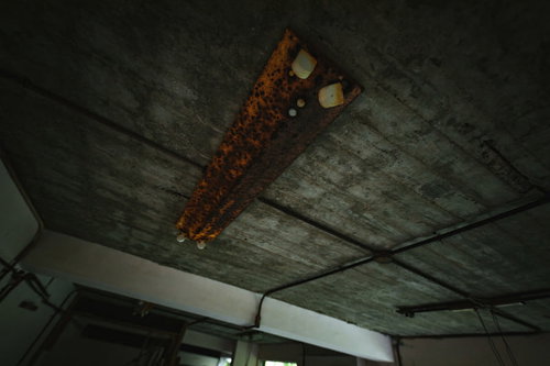 天井に設置された錆びた蛍光灯と劣化したコンクリート壁（廃墟）