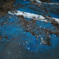 青いタイルが剥がれた廃墟のプール跡 コンクリート露出の崩壊風景の写真