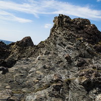 青空の下に露出した泥岩と砂岩が引きちぎられて混ざったメランジ堆積物の写真
