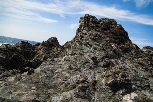 青空の下に露出した泥岩と砂岩が引きちぎられて混ざったメランジ堆積物