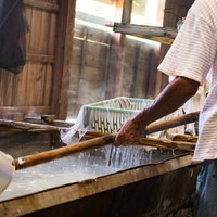 薪の窯で煮詰めた海水からゴミを取り除く製塩作業の写真