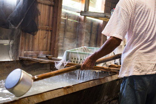 薪の窯で煮詰めた海水からゴミを取り除く製塩作業