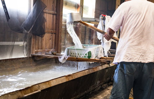 徳之島の伝統製塩、海水を沸騰させ浮遊物を取り除くましゅの作業