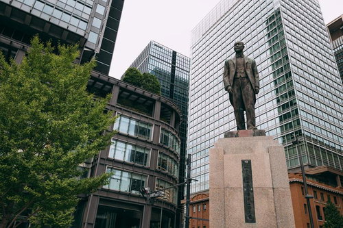 高層ビル群に囲まれた井上勝像の銅像と石碑