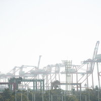 港湾工業地帯にそびえ立つガントリークレーンの写真