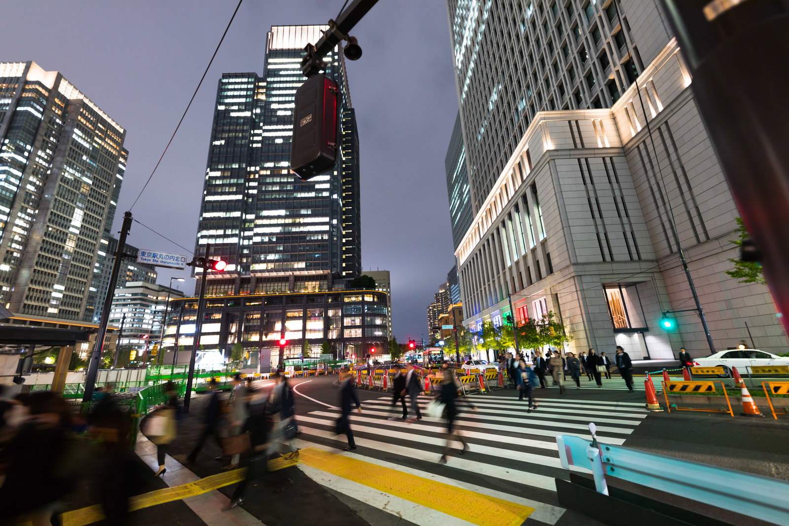 東京丸ノ内の夜景の中、横断歩道を渡るスーツ姿の会社員たち