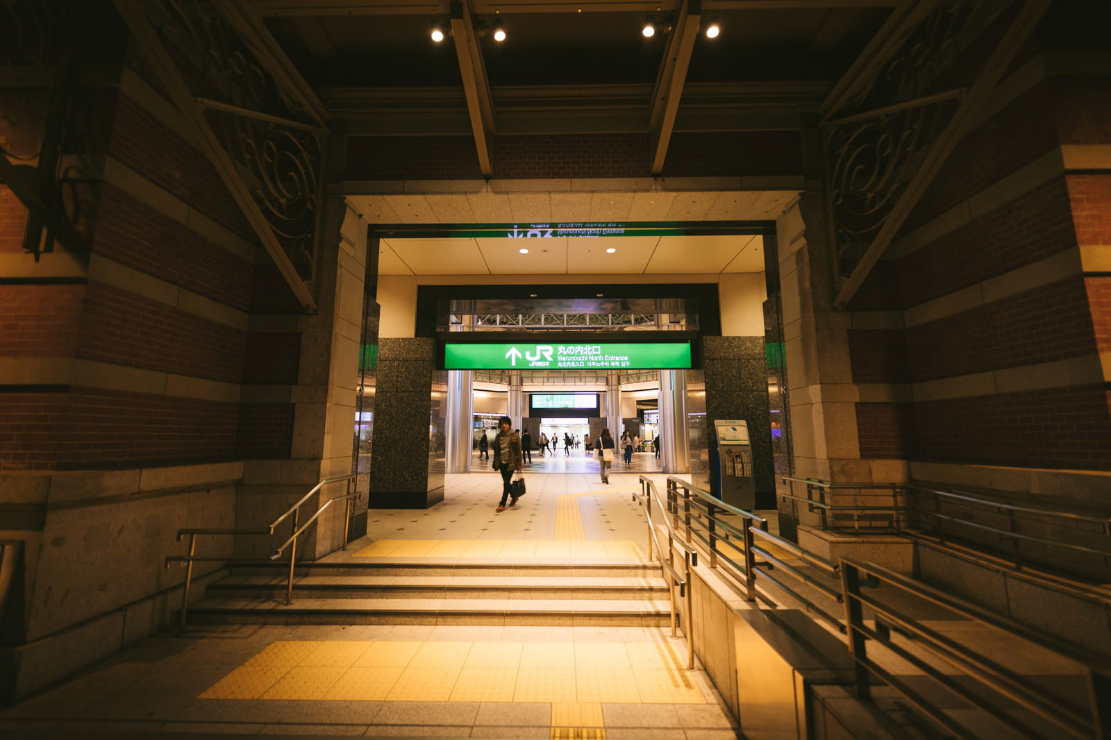 夜のJR東京駅丸の内北口改札前通路を歩く人々