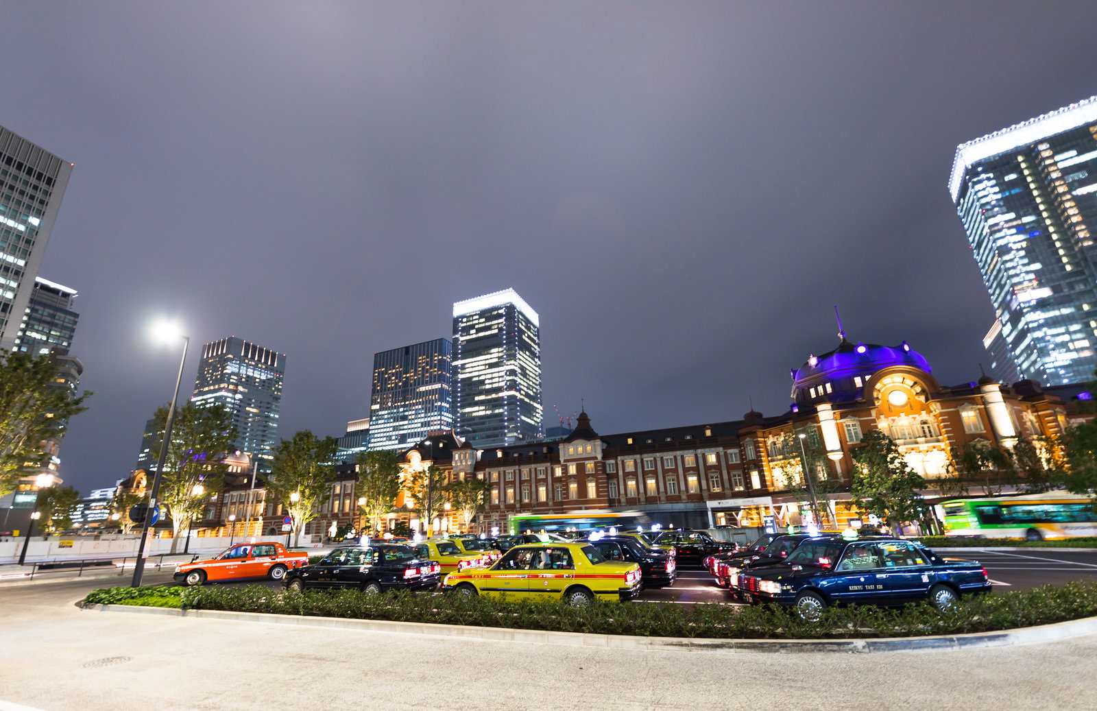 夜の東京駅前でタクシーが停車している停留所と背景の高層ビル群