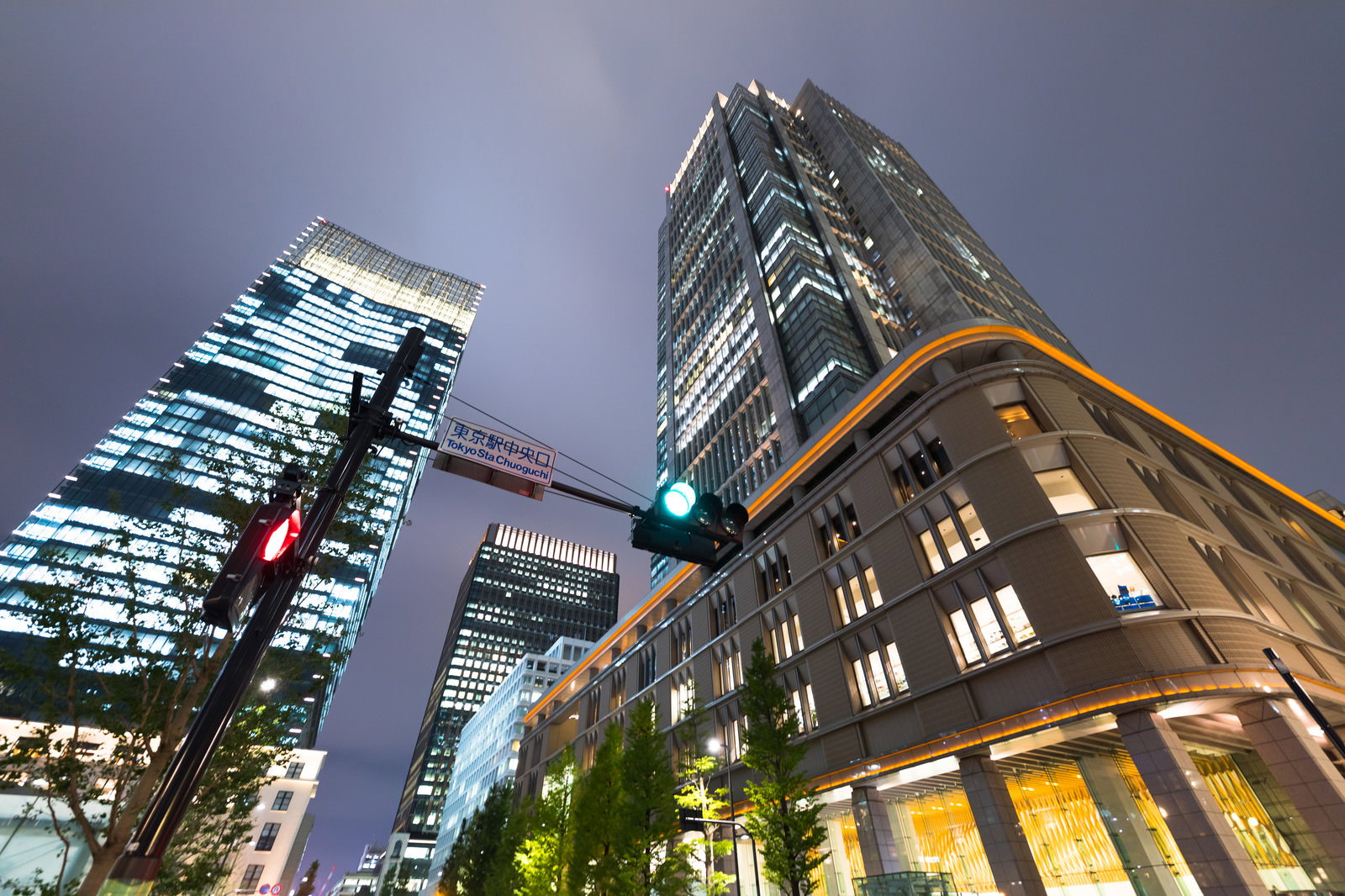 夜にライトアップされた高層ビル群と信号機、街路樹のある都市風景