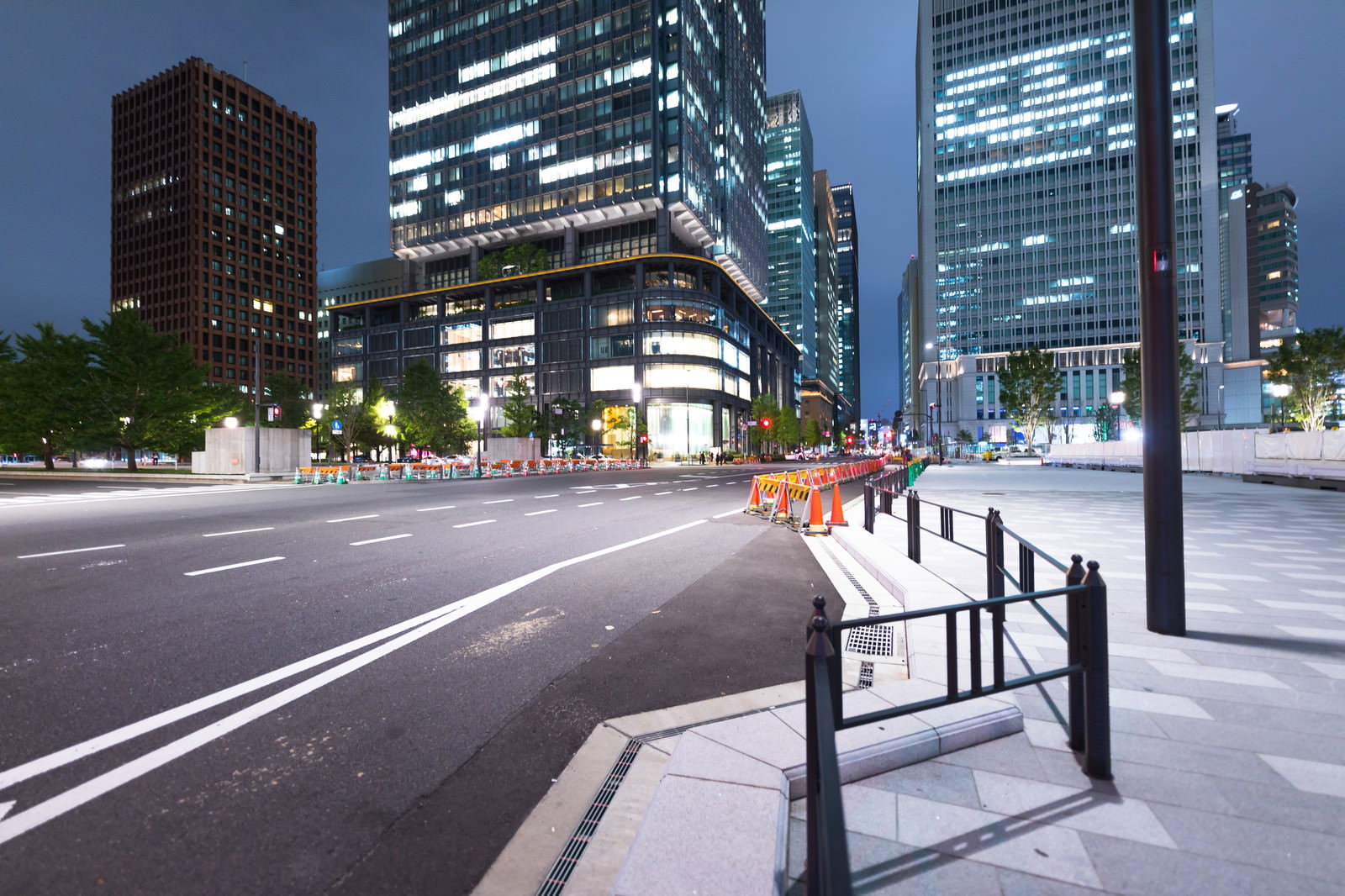 夜景の東京駅前で光る高層ビル群と車のライトの軌跡が見える幹線道路