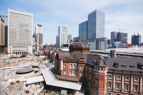 昼間の駅前で工事が続く東京駅丸の内駅舎と高層ビル群