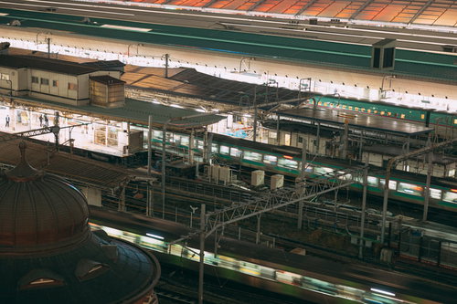 駅ホームを通過する緑色の電車が走る駅構内の