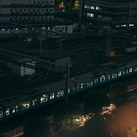 夜間の東京駅構内を走る照明灯の明るい電車と線路風景の写真