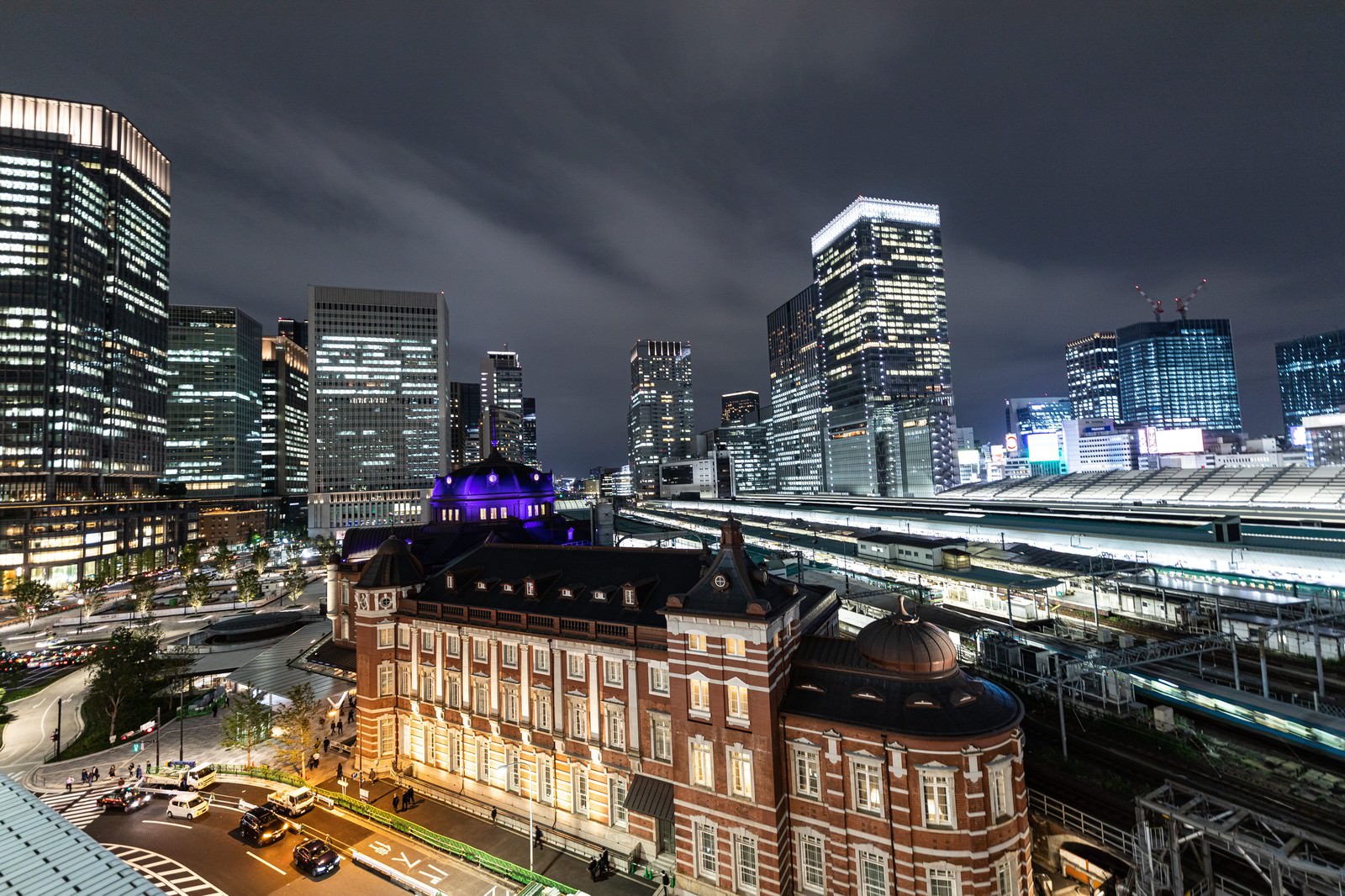 夜景に浮かぶ東京駅の赤レンガ駅舎と背後の丸の内高層ビル群