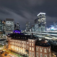 夜の東京駅越しに見る丸の内ビル群の夜景と都市風景の写真