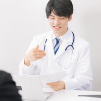 患者に医療アドバイスを提供する若い男性医師の笑顔の写真