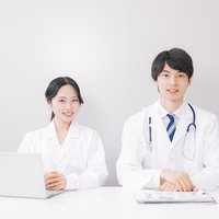 デスクで仕事をする男性と女性の医師の親しみやすい笑顔の写真