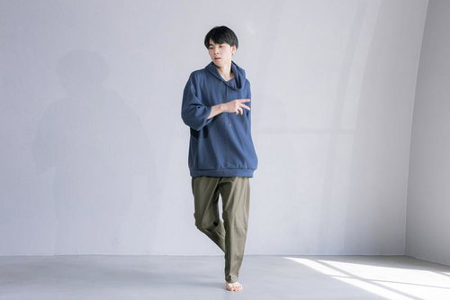 青いパーカーとカーキ色のパンツを着た男性のダンスポーズ