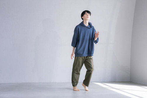 紺色パーカーとカーキパンツで片足を持ち上げてダンスする男性