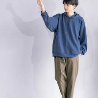 白い壁を背景にした若い男性のポートレート、腕を上げたポージングの写真