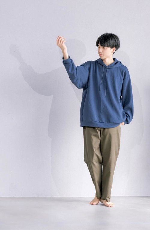 白い壁を背景にした若い男性のポートレート、腕を上げたポージング