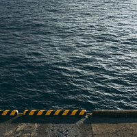 黄色と黒のストライプが施されたコンクリート製の桟橋と海の写真