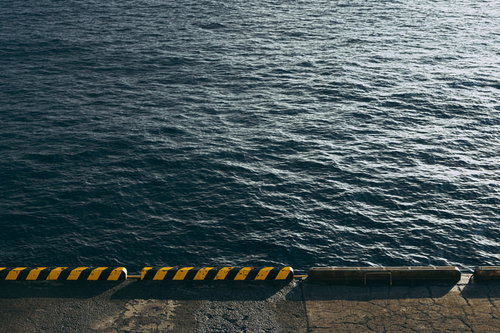 黄色と黒のストライプが施されたコンクリート製の桟橋と海