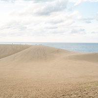 鳥取砂丘越しに広がる水平線と青い海の写真