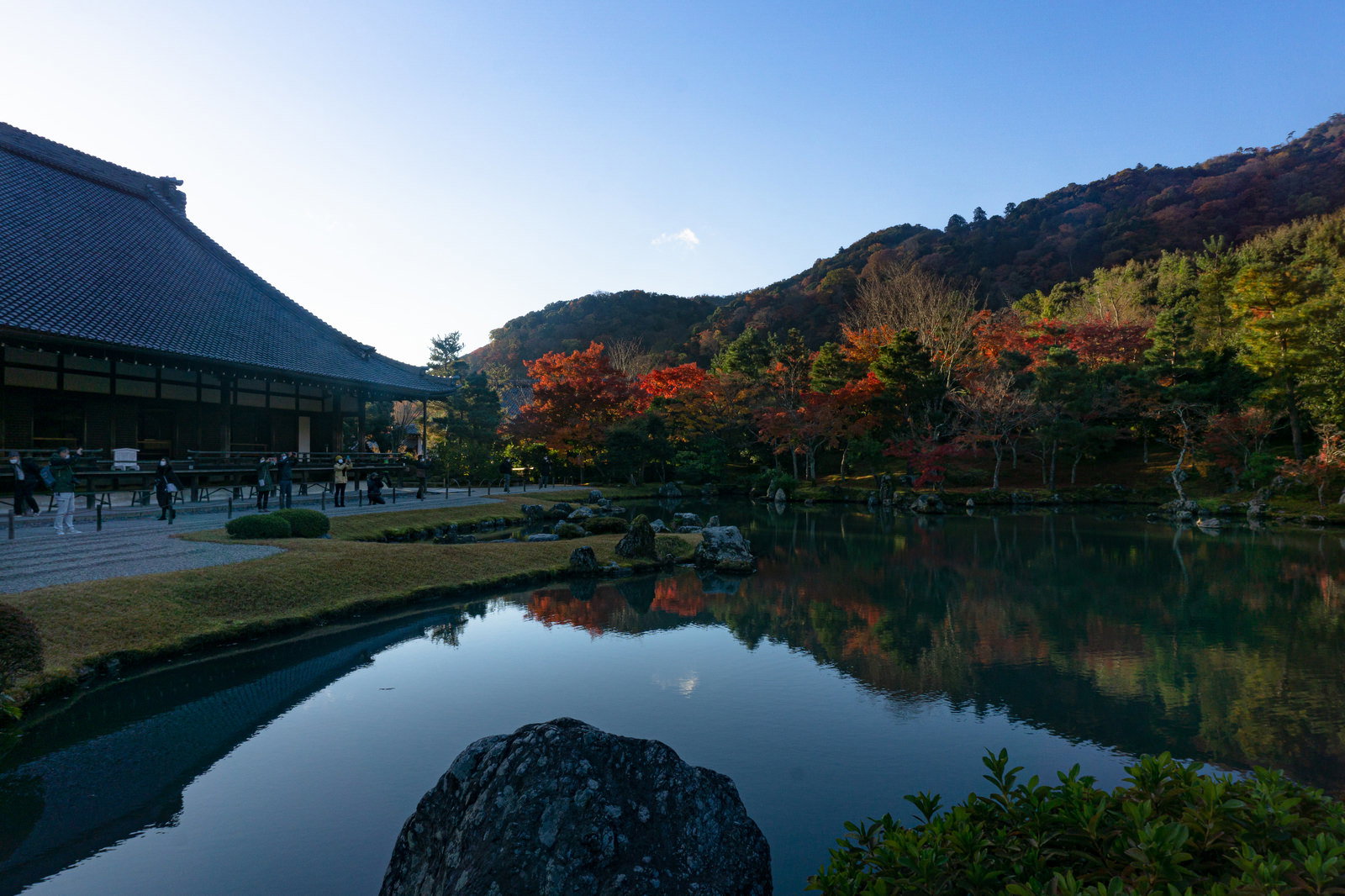 曹源池庭園で紅葉を撮影する観光客たちと水鏡に映る秋の風景