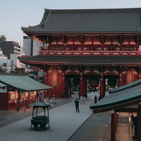 日暮れを迎える浅草寺の境内、夕焼けに染まる本堂と参拝客の写真