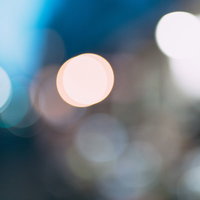 青い背景に浮かぶ玉ボケ。白く輝く光の煌めきの写真