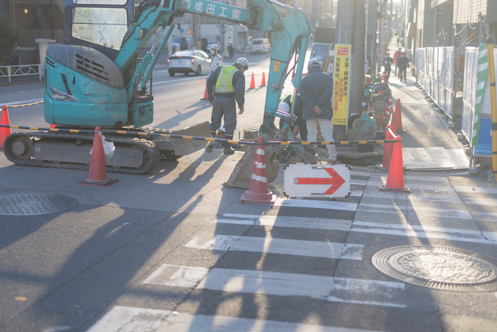 道路工事現場で交通整理を行う作業員とショベルカー