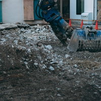 重機周辺に積み上げられた工事現場の瓦礫と土砂の写真