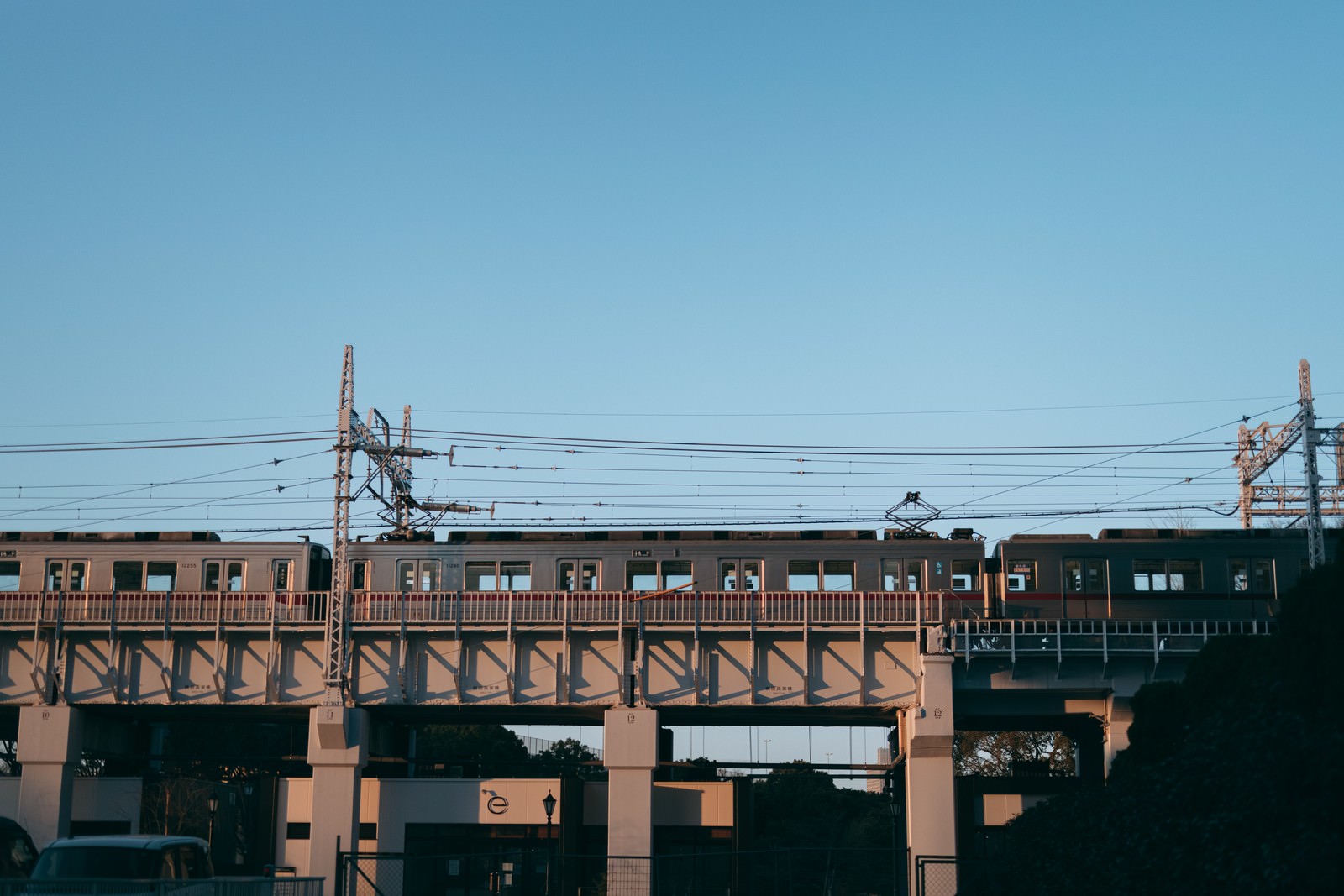 青空を背景にコンクリート高架橋上の電車と電線