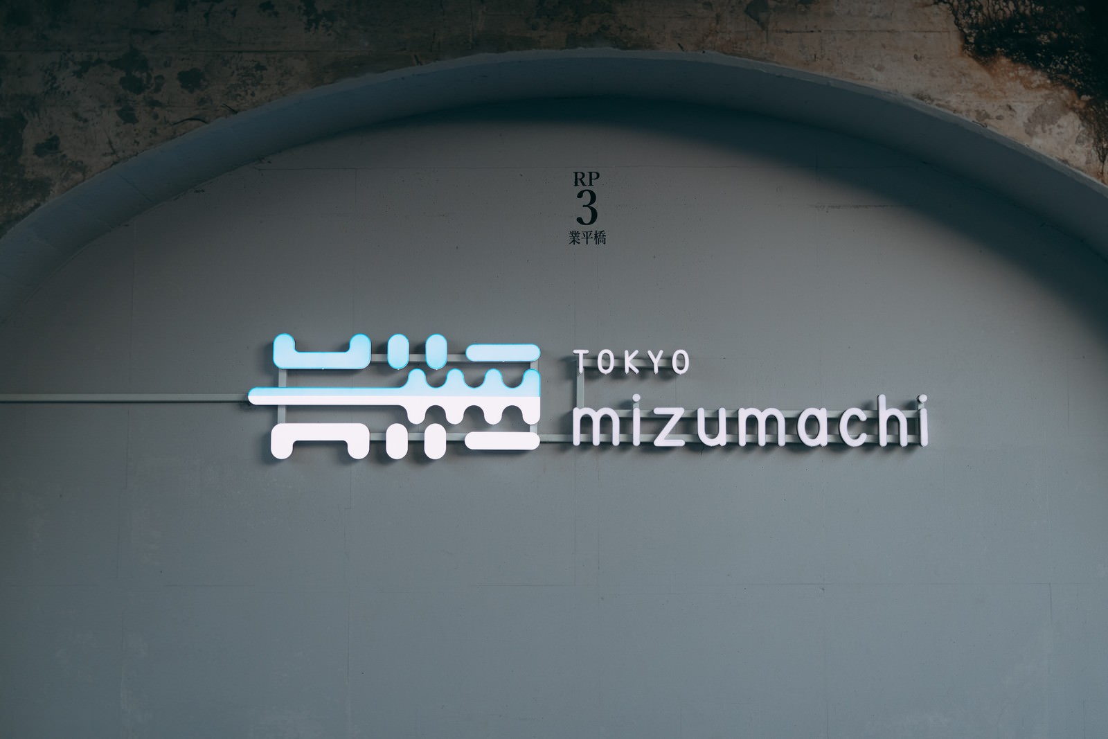 A white signboard of Tokyo Mizumachi is installed on the exterior wall of the building.