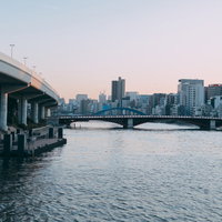 夕暮れ時の隅田川に架かる橋と簡易船着場の都市風景の写真