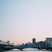 夕焼けに染まる隅田川と橋、建物群の夜景。東京の都市風景の写真