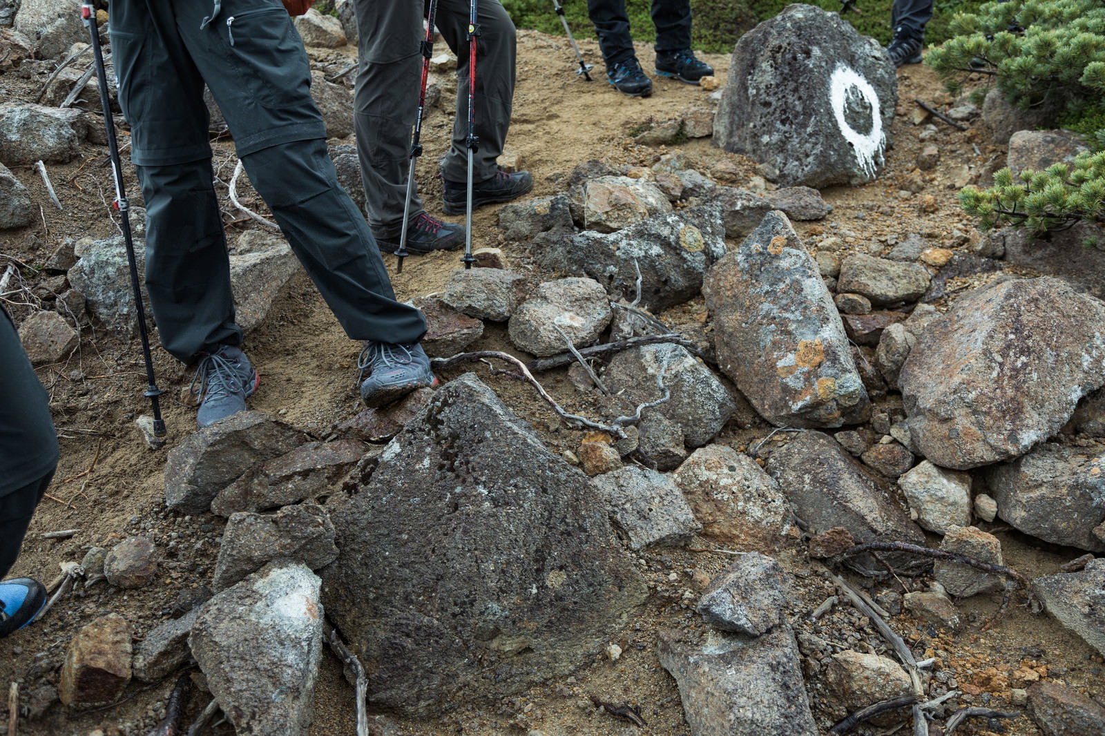 岩場で休憩している登山者の足元と周囲の石や岩