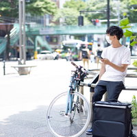 配達依頼を受付けているスマホを操作する配達パートナーの男性の写真