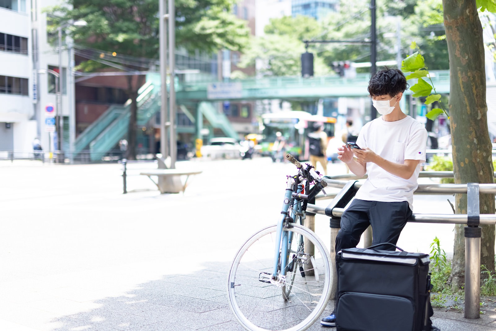 白いシャツを着た男性がフードデリバリーの配達で自転車に乗っている［モデル：TSURUTAMA］