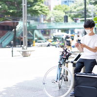 お昼時にフードデリバリーの配達準備をする男性の写真